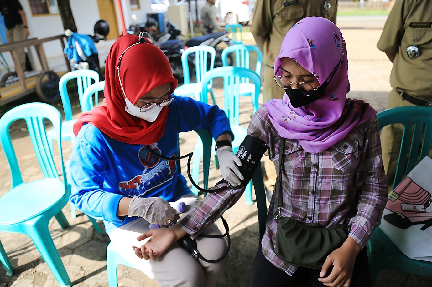 A health worker checks the blood pressure of Siti Mustabsyiroh at the Tayukulon Village Head Office. Siti recently had a heart surgery that made her currently ineligible for vaccination (photo by: AIHSP Documentation Team)